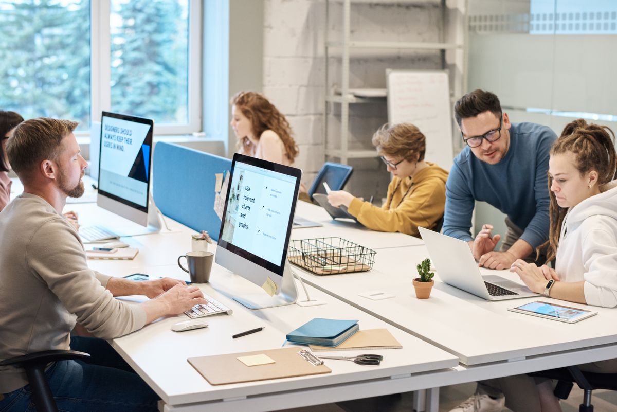 Medewerkers werken samen achter een laptop, illustratie bij een AI-chatbot voor medewerkers
