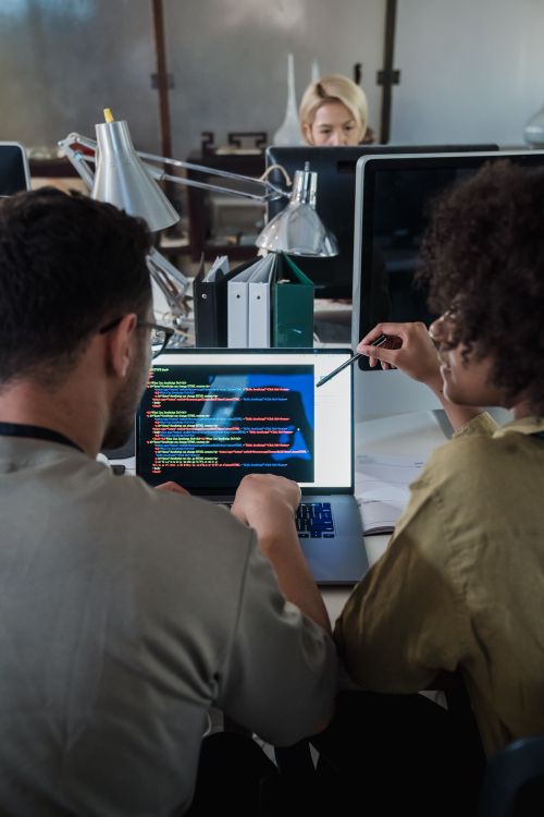 Twee ontwikkelaars werken samen aan softwarecode op een laptop in een modern kantoor