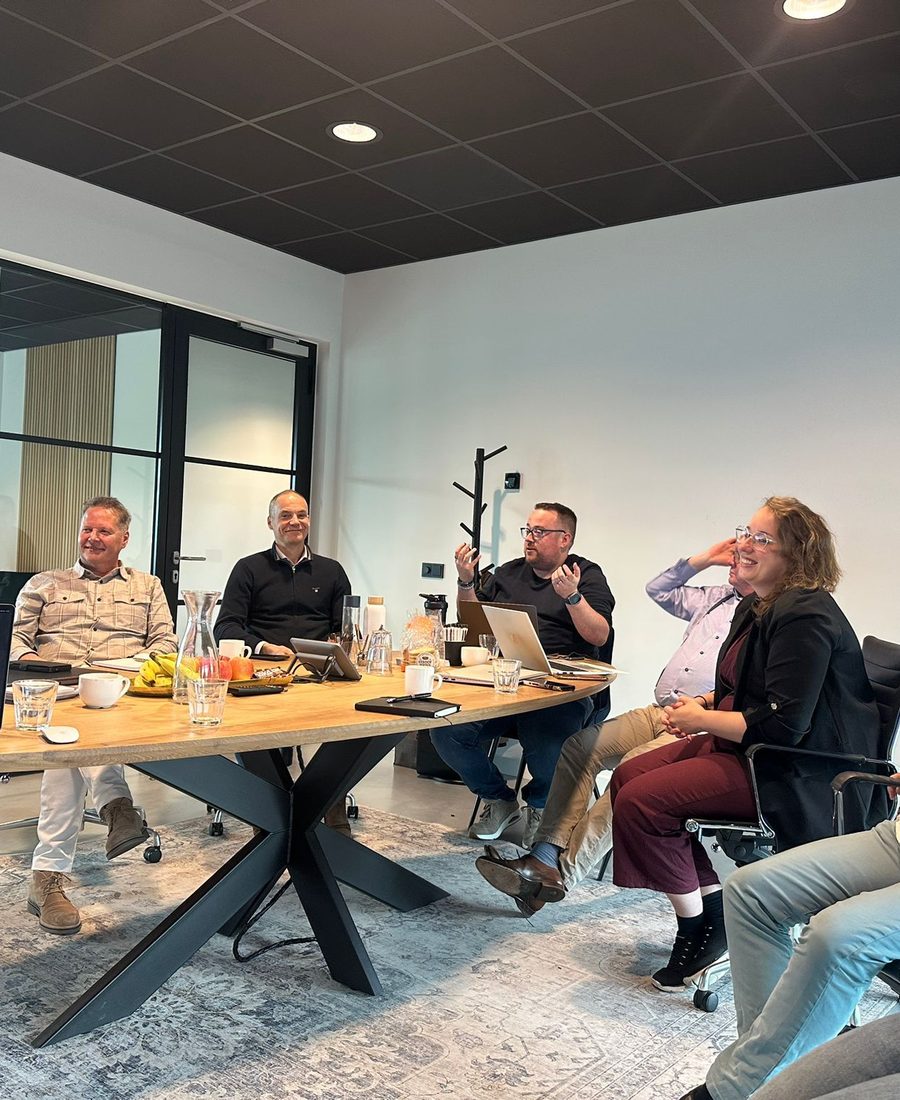 Ondernemers in gesprek aan een lange tafel op kantoor