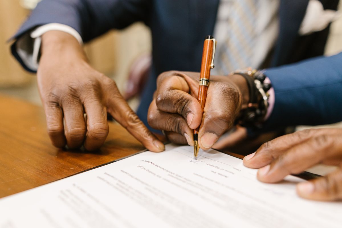 Close-up van een persoon die een contract ondertekent, bij AI compliance in het notariaat