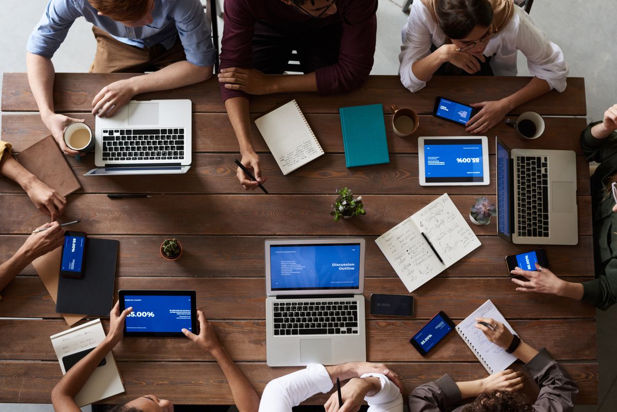 Team bespreekt AI implementatie op een notariskantoor aan een houten tafel met laptops
